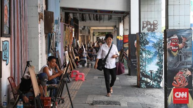 Di sepanjang trotoar jalan Pintu Besar Selatan Tiga, Jakarta, Kota, kita dapat melihat jajaran pelukis jalanan menggarap lukisan pesanan dengan berbagai karakter dan kepiawaiannya. Pelukis jalanan ini menjadi salah satu destinasi wisata di kota Tua Jakarta. CNNIndonesia/Safir Makki