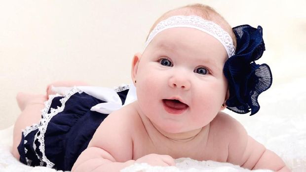 close-up of a cute little baby girl smiling at camera on light background