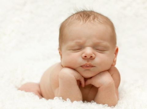 Adorable newborn propped up on own hands.