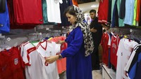 Perempuan Iran berbelanja jersey sebelum laga Iran vs Kamboja digelar. (Foto: Vahid Salemi/AP Photo)