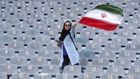 Perempuan Iran mengibarkan bendera negaranya di tribune Stadion Azadi. (Foto: Vahid Salemi/AP Photo