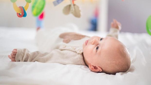 Happy baby playing in baby gym toy