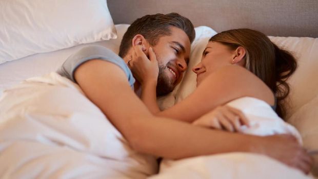 Top view of beautiful happy young couple lying on bed and hugging