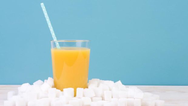 Glass of orange juice with plenty of sugar cubes