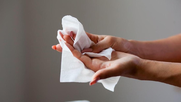 Young woman cleaning fingers and hands with wet wipes