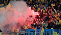Para pendukung Ukraina menyalakan flares. REUTERS/Valentyn Ogirenko.