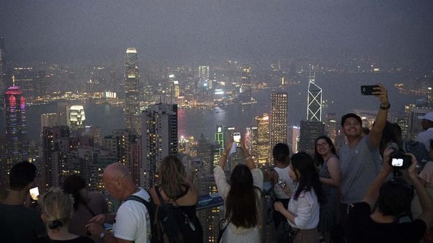 In this Oct. 9, 2019 photo, tourists take photos in a foggy evening at the Victoria Peak in Hong Kong. The body-blow of months of political protests on Hong Kong’s tourism is verging on catastrophic for one of the world’s great destinations. Geared up to receive 65 million travelers a year, the city’s hotels, retailers, restaurants and other travel-oriented industries are suffering. But some intrepid visitors came specifically to see the protests and are reveling in deep discounts and unusually short lines at tourist hotspots.(AP Photo/Felipe Dana)