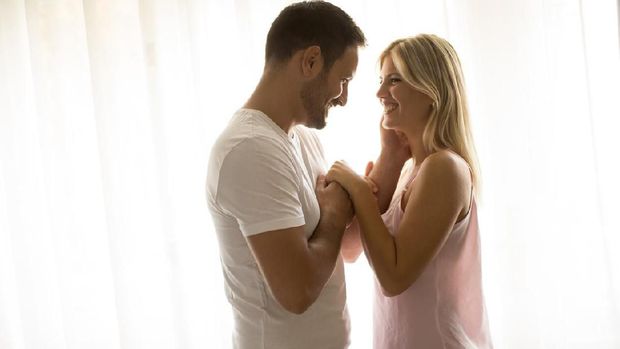 Side view at romantic couple standing by window in the room