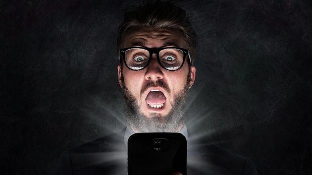 Nerd with glasses is shocked after reading a sms