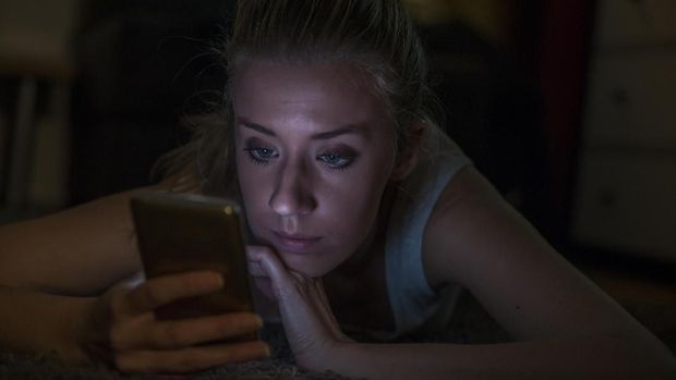Portrait of an upset woman reading a text message on her phone at night at home