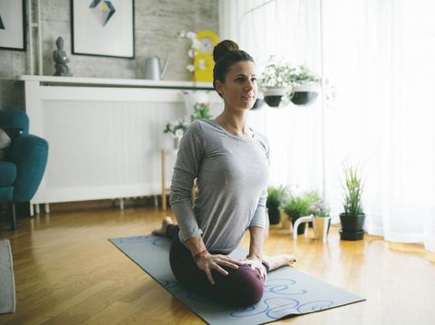 Young woman practicing iyengar yoga at home in her living room.
