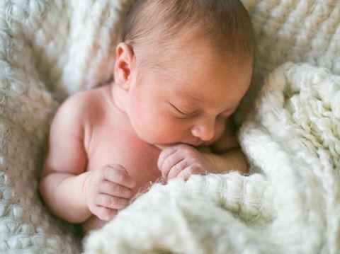 Sweet newborn baby sleeps in a basket. Beautiful newborn boy with bear toy.