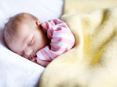 Sweet newborn baby sleeps in a basket. Beautiful newborn boy with bear toy.