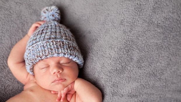 Sweet newborn baby sleeps in a basket. Beautiful newborn boy with bear toy.