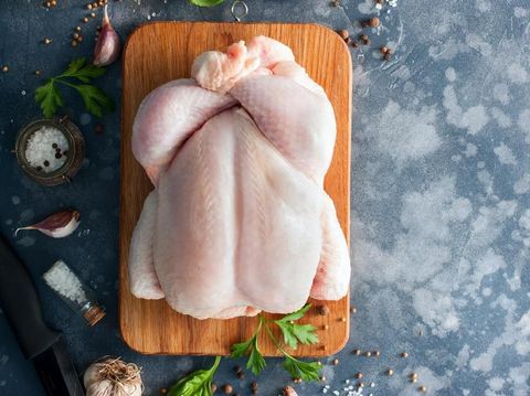 Whole raw chicken on a wooden board with spices for cooking, top view, horizontal, copy space