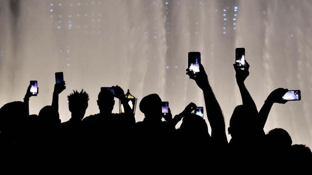 Visitors take pictures with their telephones of the fountains in front of Burj Khalifa, the worldís tallest building, in Dubai on October 31, 2019. (Photo by GIUSEPPE CACACE / AFP)