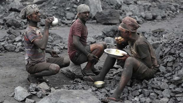 In this Oct. 23, 2019, photo, laborers eat lunch at a coal loading site in the village of Godhar in Jharia, a remote corner of eastern Jharkhand state, India. The fires started in coal pits in eastern India in 1916. More than a century later, they are still spewing flames and clouds of poisonous fumes into the air, forcing residents to brave sizzling temperatures, deadly sinkholes and toxic gases. (AP Photo/Aijaz Rahi)