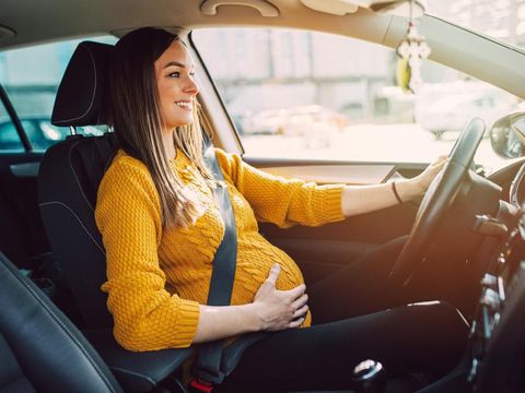 Pregnant woman driving with safety belt on in the car.