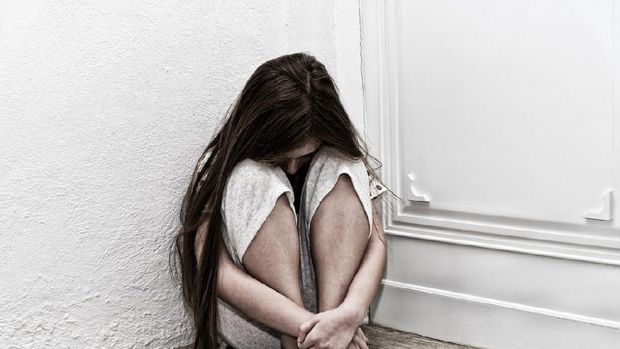 Neglected lonely child against the white wall.  Little girl crying in the corner. Violence concept.