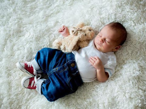 Fashionable little newborn baby boy, sleeping in the afternoon at home in bed with cute toy