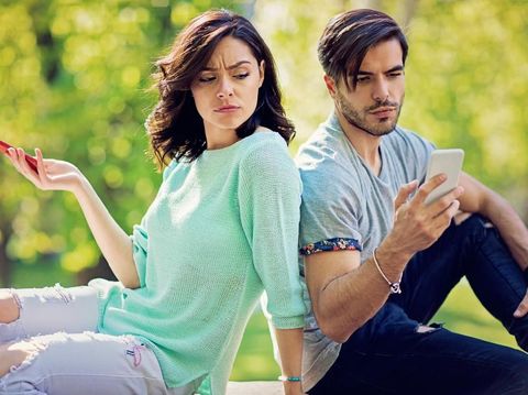 Couple in conflict is texting in the park and sulking each other