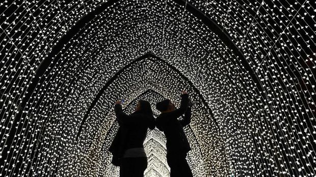 Visitors walk through the 'By Frost' tunnel of lights during a photocall at Kew Gardens in south west London, on November 19, 2019, during an event to promote the launch of the 