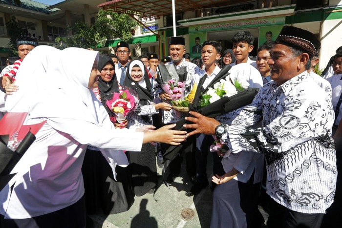 Pelajar memberikan bunga pada gurunya seusai upacara peringatan hari guru nasional dan dan HUT Persatuan Guru Republik Indonesia (PGRI) di MTsN Model, Banda Aceh, Aceh, Senin (25/11/2019). Peringatan hari guru nasional yang bertepatan dengan HUT ke-74 PGRI menjadi momentum memberikan penghargaan dan ungkapan terima kasih kepada guru yang telah mendidik serta meningkatkan kualitas sumber daya manusia generasi penerus pembangunan bangsa. ANTARA FOTO/Irwansyah Putra/foc.