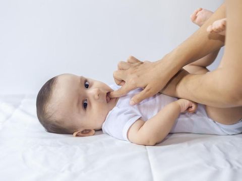 Baby boy teething pain. Little 6-month baby having teeth pains. Mother rubbing gel to her little baby boy's teeth. Medicine and health concept.
