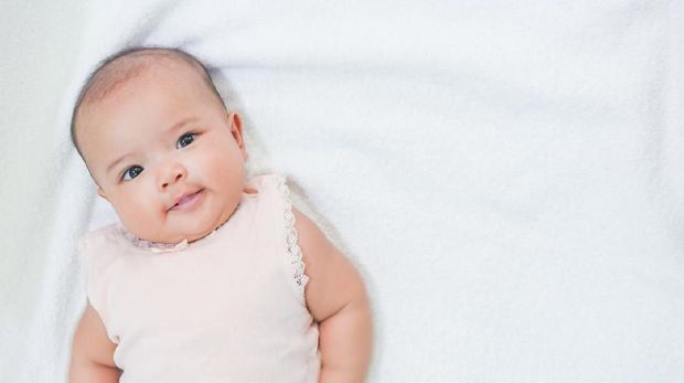 Asian newborn baby gives a sweet smile on white background.