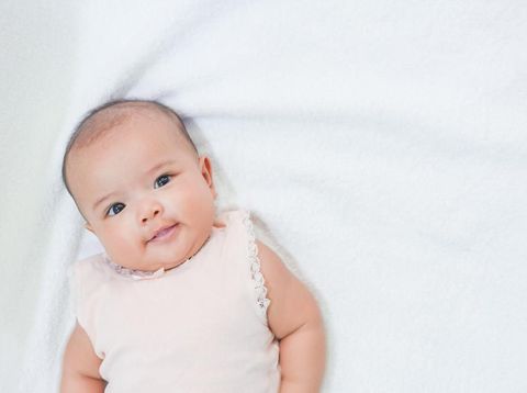 Asian newborn baby gives a sweet smile on white background.