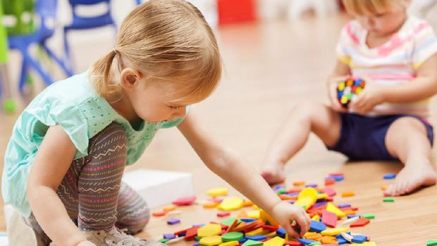 Young woman with his toddler son playing with colorful plastic blocks. Family leisure activity
