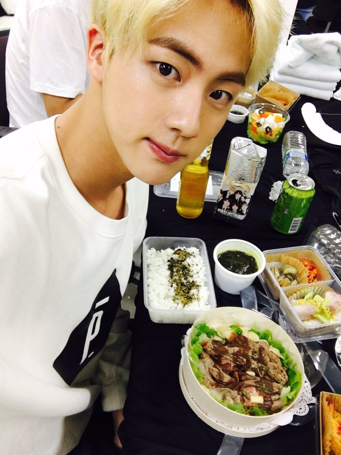  Sebelum menjalankan berbagai aktivitasnya, Jin sempatkan selfie dengan makanan yang dia santap. Bekal makanan ini dilengkapi nasi putih dan lauk yang lengkap. Foto: Twitter & Instagram BTS