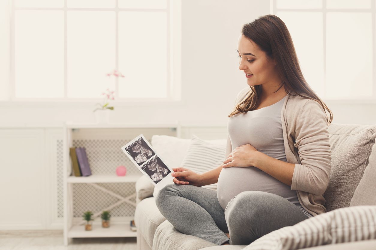 Pregnant woman looking at her baby sonography. Happy expectant lady enjoying first photo of her unborn child, anticipating her future life, copy space
