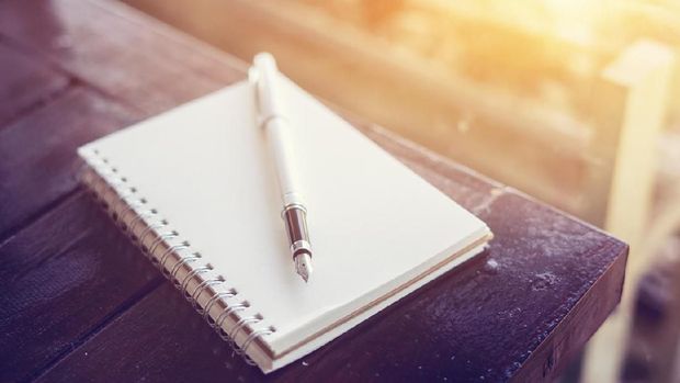 pen on the desk,Open a blank white notebook on wooden table and green bokeh background ,vintage color,selective focus