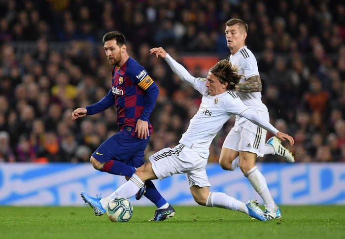 BARCELONA, SPAIN - DECEMBER 18:  Lionel Messi of Barcelona is tackled by Luka Modric of Real Madrid during the Liga match between FC Barcelona and Real Madrid CF at Camp Nou on December 18, 2019 in Barcelona, Spain. (Photo by Alex Caparros/Getty Images)