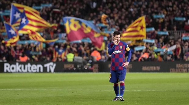 Barcelona's Lionel Messi waits while stewards collect balls with the message 