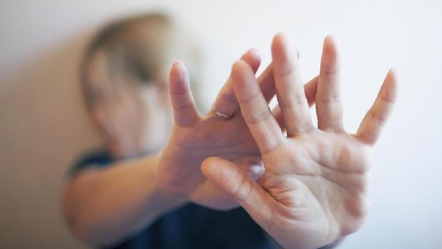 A young woman protects herself by hand