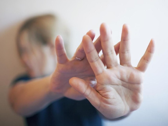 A young woman protects herself by hand