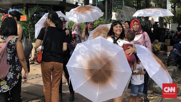 Nia Umar dan payung putih berbercak cokelat menyuarakan hak ibu menyusui di aksi jalan ke Istana di Hari Ibu, Minggu (22/12).
