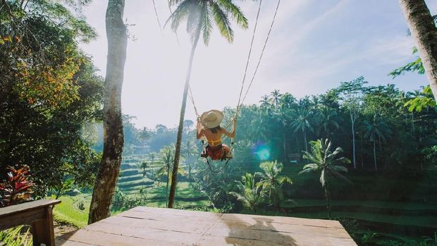 Beautiful girl visiting the Bali rice fields in tegalalang, ubud. Using a swing over the jungle. Concept about people, wanderlust traveling and tourism lifestyle