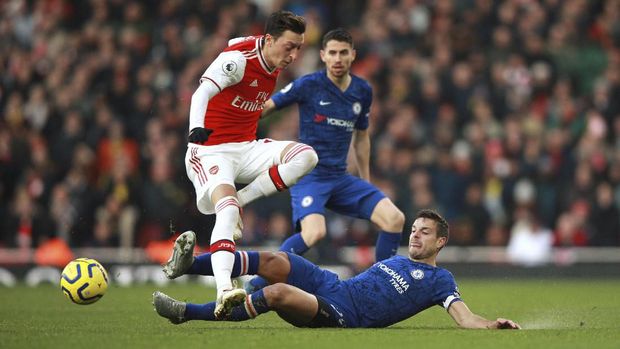 Arsenal's Mesut Ozil, left, is tackled by Chelsea's Cesar Azpilicueta during the English Premier League soccer match between Arsenal and Chelsea, at the Emirates Stadium in London, Sunday, Dec. 29, 2019. (AP Photo/Ian Walton)