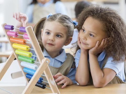 Happy schoolgirl preschool girl with book near school board blackboard