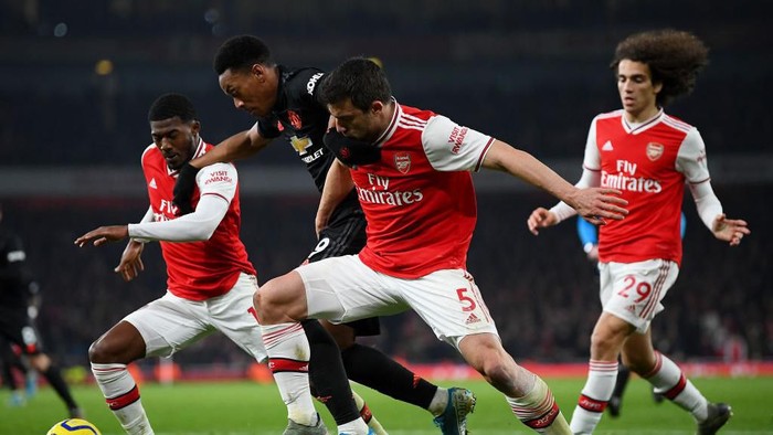 LONDON, ENGLAND - JANUARY 01: Anthony Martial of Manchester United is challenged by Ainsley Maitland-Niles (L) and Sokratis Papastathopoulos of Arsenal (R) during the Premier League match between Arsenal FC and Manchester United at Emirates Stadium on January 01, 2020 in London, United Kingdom. (Photo by Clive Mason/Getty Images)