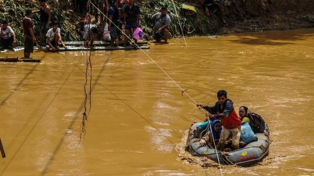 Sejumlah relawan membantu warga menyeberangi Sungai Ciberang untuk dievakuasi ke tempat aman di Kampung Susukan,  Lebak,  Banten,  Kamis (2/1/2020). Proses evakuasi warga hanya bisa mengandalkan perahu karet karena jembatan penghubung di lokasi itu hancur diterjang banjir bandang hari Rabu (1/1). ANTARA FOTO/Muhammad Bagus Khoirunas/af/nz