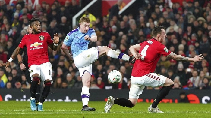 Manchester Citys Kevin De Bruyne, centre attempts a shot on goal, which is blocked by Manchester Uniteds Phil Jones, right, during the English League Cup semifinal first leg soccer match between Manchester United and Manchester City and at Old Trafford, Manchester, England, Tuesday, Jan. 7, 2020. (AP Photo/Jon Super)
