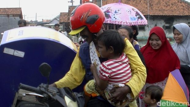 Tarmuji saat bekerja sambil menggendong anaknya