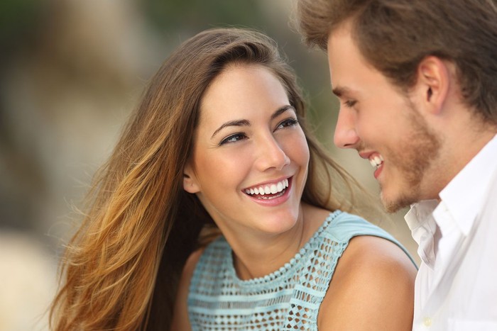 zodiak Front view portrait of a happy couple with perfect smile looking at you sititng on a couch in the living room at home in winter