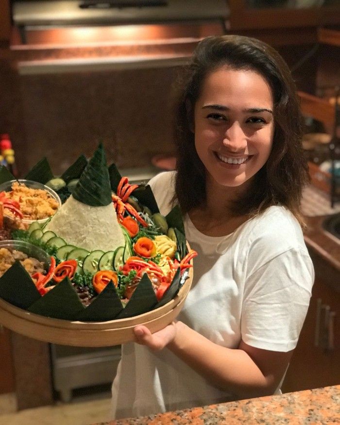 Merayakan hari spesial dengan tumpeng, serta aneka lauk lengkap, dan sayuran penuh warna, Alexandra berpose dengan manis. Foto: Instagram @got_alex