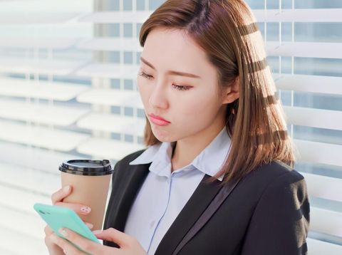 business woman feel depress and use smart phone while drinking coffee in the office