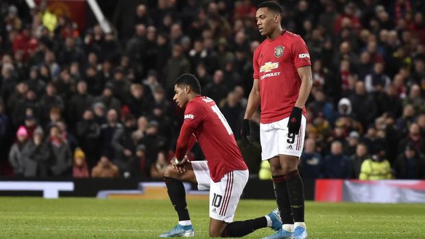 Manchester United's Anthony Martial stands next to kneeling teammate and substitute player Marcus Rashford after he sustained an injury during the English FA Cup third round replay soccer match between Manchester United and Wolverhampton Wanderers at Old Trafford in Manchester, England, Wednesday, Jan. 15, 2020. (AP Photo/Rui Vieira)